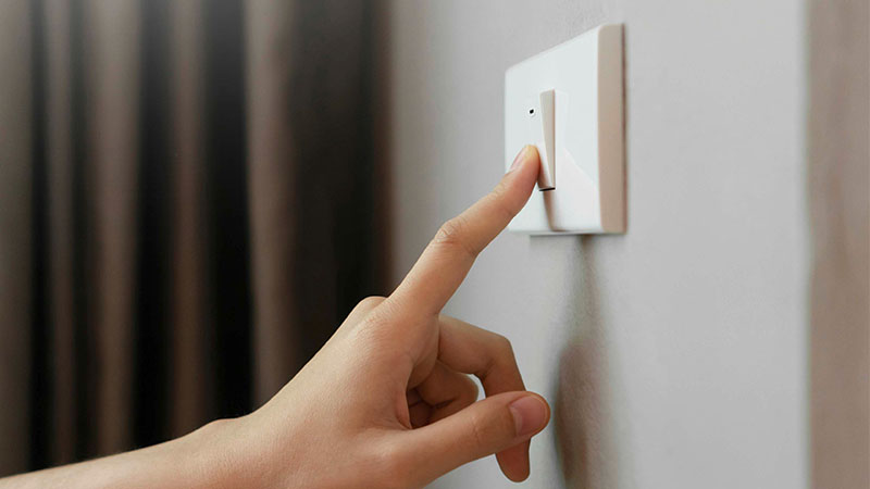 Mão a tocar em interruptor elétrico